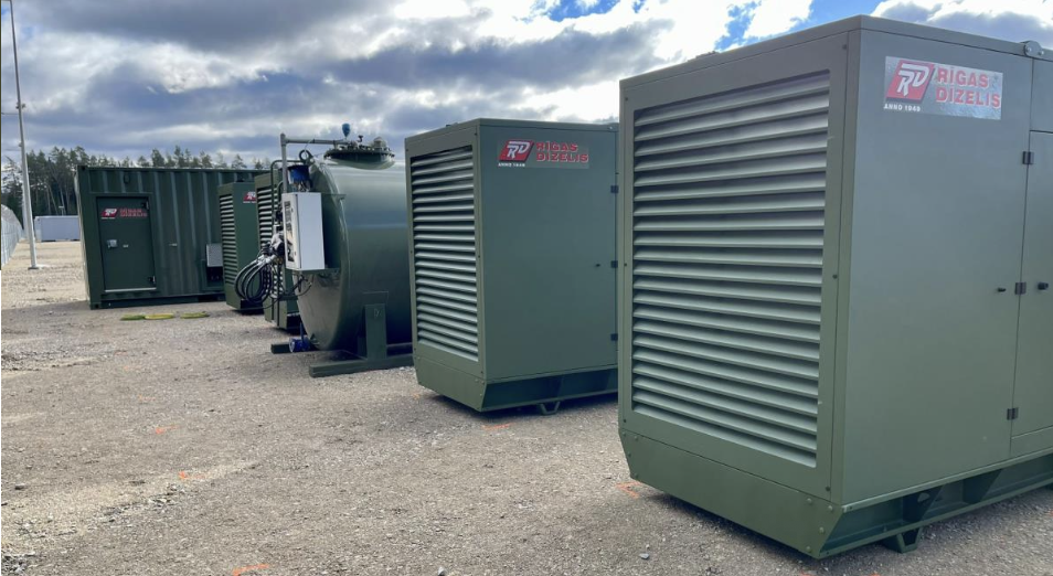 Olive-drab generator sets and fuel storage tank deployed on a gravel lot