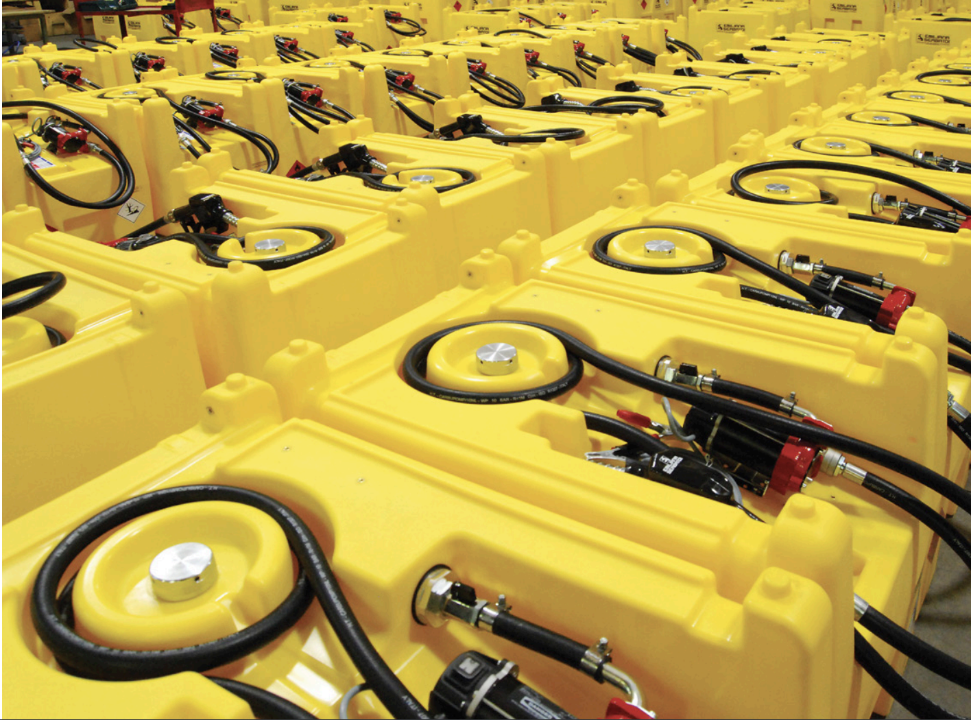 Rows of portable diesel and DEF transfer tanks ready for shipment in a distribution warehouse