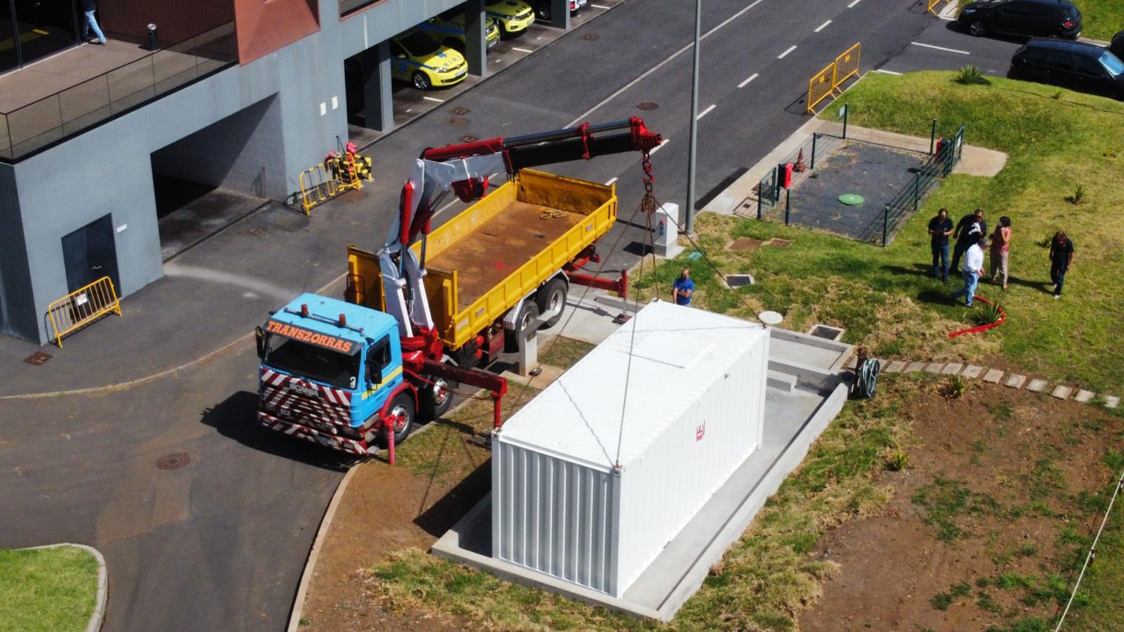 Crane truck lowering a containerized fuel farm unit onto a concrete foundation