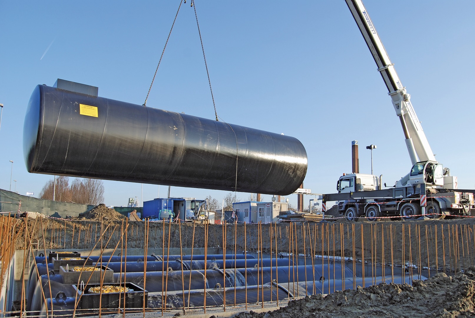 Underground storage tank being crane-lifted into an excavated tank bed