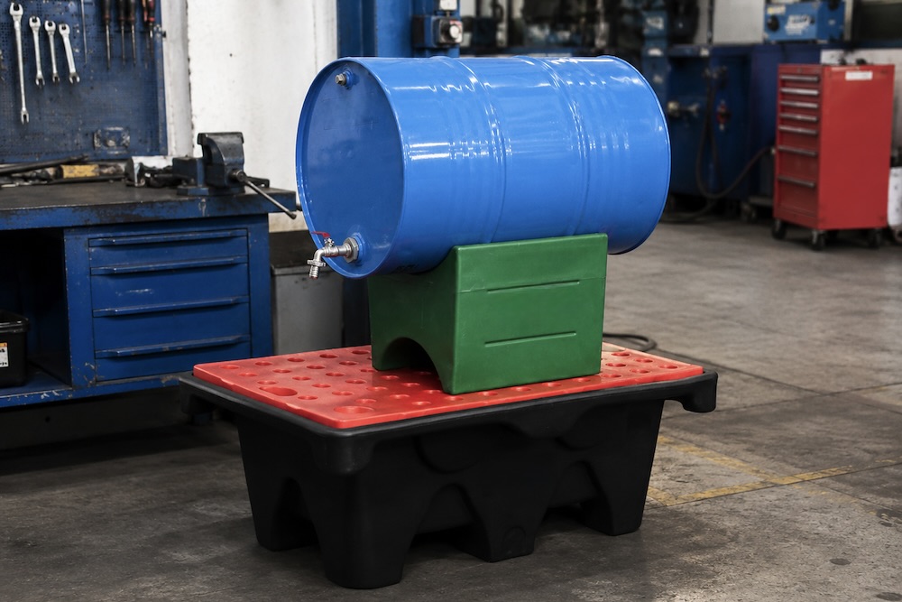 Drum dispensing stand on a bunded containment pallet in a workshop