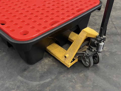 Pallet jack lifting a bunded containment platform by its forklift channels