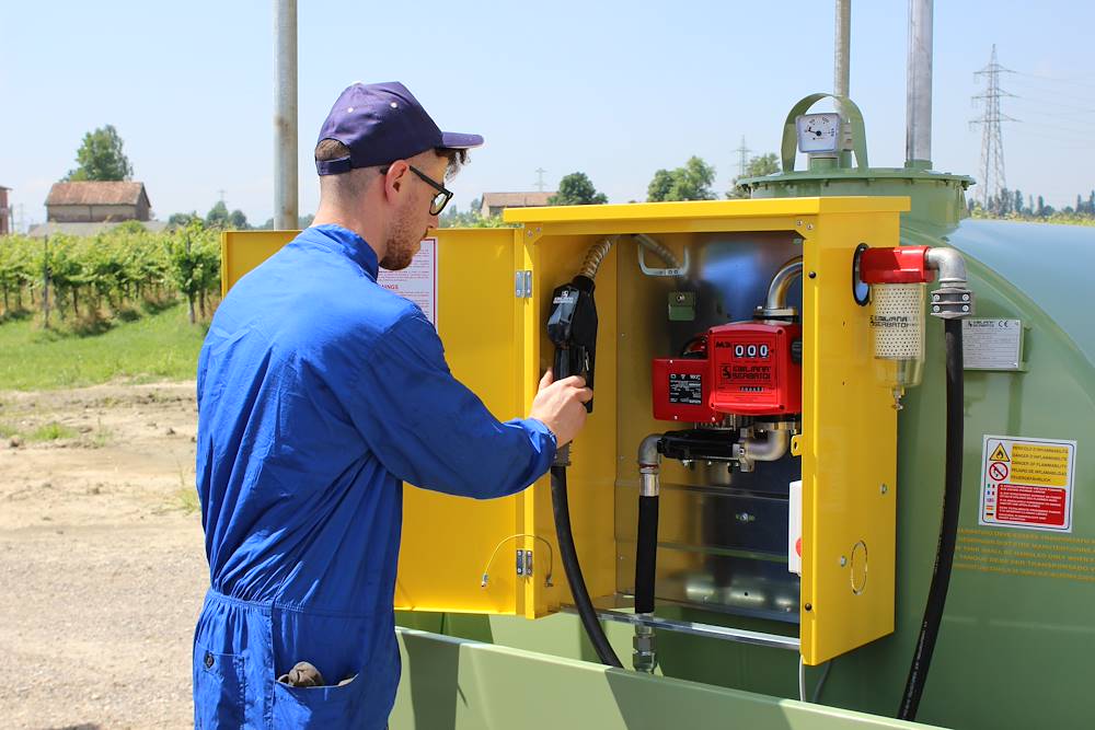 Operator dispensing fuel from a yellow cabinet with pump, meter and filtration
