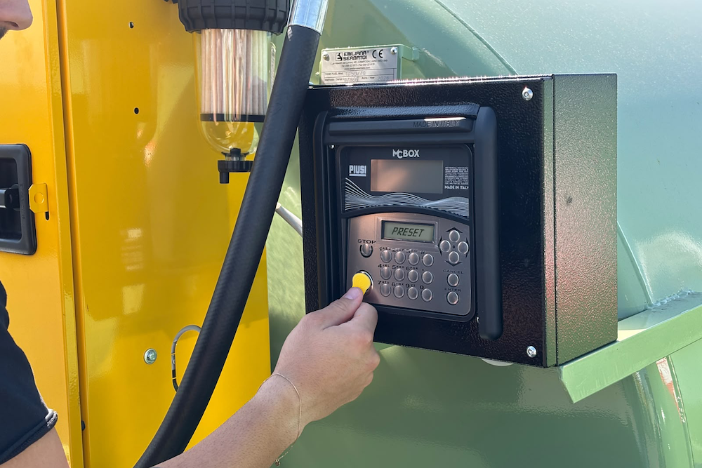 Operator entering a preset volume on a fuel management terminal at a tank